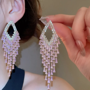Close-up of elegant gold tassel earrings with rectangular pink zircon stones on model