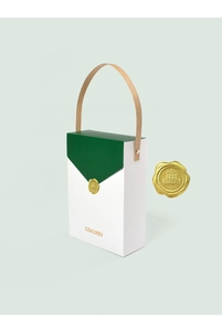 Detail of white and green gift box with gold wax seal and brown paper handle