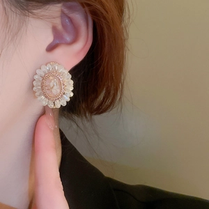Detail of floral earring with crystal petals and pink resin center worn by a model