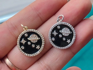 Macro detail of hand-held gold and silver enamel star pendants with cubic zirconia