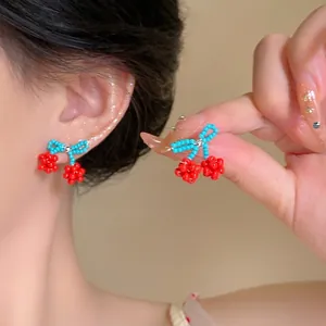 Boucles d'oreilles artisanales en perles avec nœud et cerise en bleu et rouge
