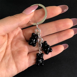 Detail of three black resin gummy bear charms on a polished silver metal keychain ring