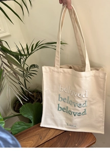 Detail of the magnetic snap closure and green gradient embroidery on a canvas tote bag