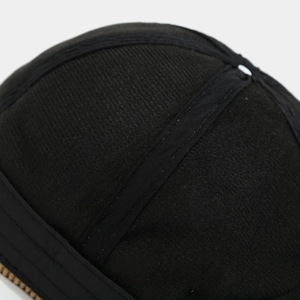 Detail shot of black corduroy beanie texture with reinforced seams and gold zipper part