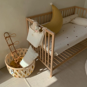 Close-up of quilted cotton baby mattress and moon pillow in a nursery setting