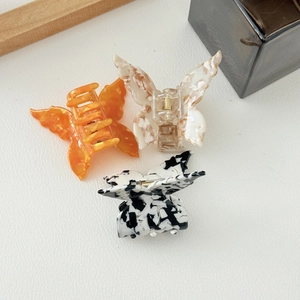 Elegant acetate butterfly hair clips in vibrant orange, marble white, and ink patterns