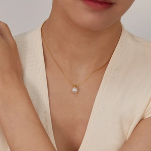 Close-up of elegant pearl pendant on a gold chain worn on the neck of a model