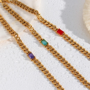 Dettaglio macro del bracciale a catena cubana dorata con gemme di zircone rettangolari