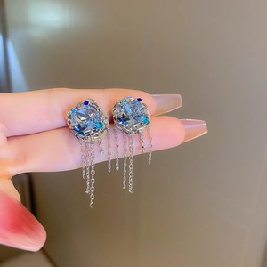 Détail de boucles d'oreilles argentées avec cristaux bleus et délicats glands en chaîne