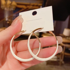 Close-up of gold and white enamel large hoop earrings on an S925 silver needle display card