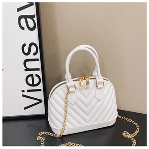 Detail of white shell jelly bag with V-shaped texture and golden chain on black surface