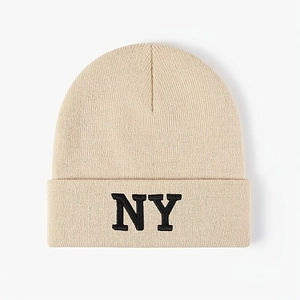 Beige knit beanie with NY embroidery, warm winter hat with turn-up cuff on white background