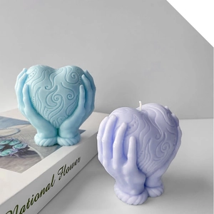 Dettaglio di mani che tengono candela a cuore con motivi di nuvole blu e viola
