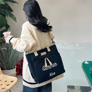 Large black canvas tote bag with Summer Nice embroidery shown on shoulder