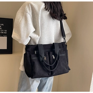 Detail view of large black corduroy tote bag with multiple pockets and shoulder strap