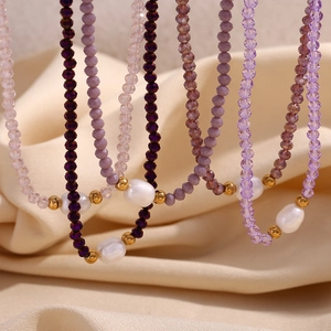 Detailed shot of purple crystal beaded necklace with freshwater pearls on beige satin