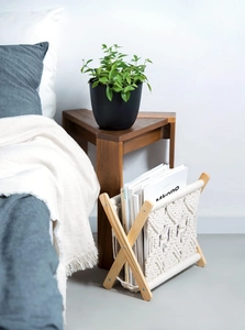 Detail of macramé magazine rack with cotton rope texture and wooden X-frame stand