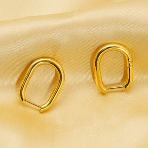 Polished 18k gold plated titanium steel U-shaped hoop earrings on elegant champagne silk