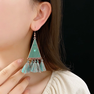 Detail of bohemian triangle tassel earring with turquoise bead on a model's ear