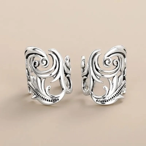 Close-up of vintage silver ear cuffs with intricate filigree texture and antique finish