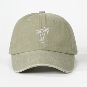 Close-up detail of white palm tree embroidery on olive green washed cotton baseball cap