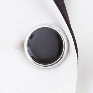 Gros plan du blazer blanc contrasté avec d'élégants boutons croisés noirs et argentés
