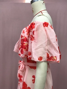 Detail eines schulterfreien Blumenkleids mit rosa Schleifengürtel und Rüschenärmeln