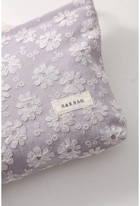 Détail de la trousse en toile lavande avec broderie marguerite 3D et étiquette tissée
