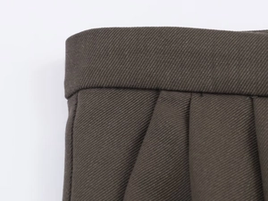 Detailed close-up of dark olive twill fabric and pleated stitching on a suit skirt