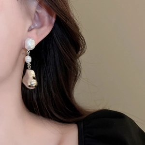 Gros plan de boucles d'oreilles en perles baroques irrégulières sur l'oreille du modèle