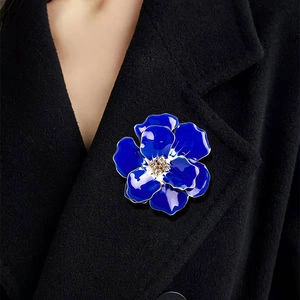 Elegant royal blue enamel flower brooch with rhinestones worn on a black wool jacket