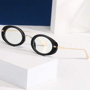 Y2K vintage small oval sunglasses with black frames and gold metal temples on a stone pedestal