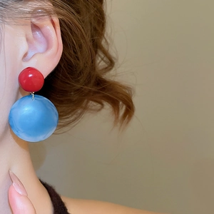 Close-up of red and sky blue resin drop earrings on a model with minimalist design