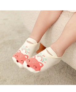 Detail of pink cotton baby floor socks with cartoon fox and straps on plush carpet