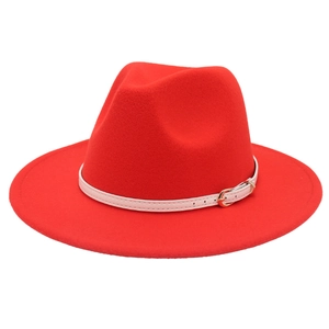 Detailed view of red jazz fedora hat featuring white leather strap and gold metal buckle