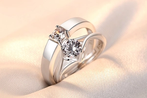 Close-up of couple's crown rings with round zircon on champagne silk background