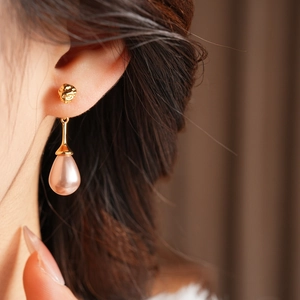 Macro shot of elegant drop earrings featuring pink waterdrop pearls and golden studs