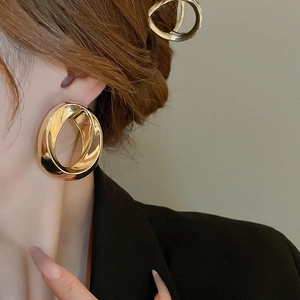 Detail view of geometric golden layered metal hoop earrings on model with high gloss finish