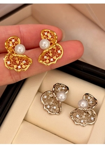 Macro shot of twisted metal wirework stud earrings with a large pearl and zircons