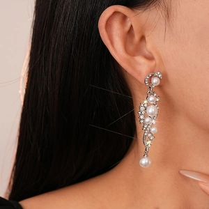 Close-up of elegant long drop earrings with white pearls and sparkling rhinestones
