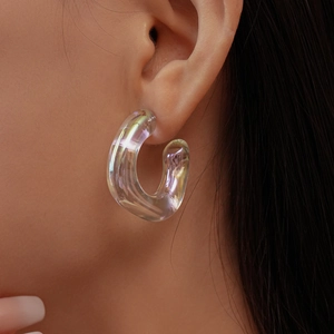 Close-up of translucent iridescent acrylic C-shaped earrings with aurora rainbow reflections