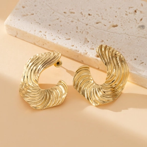 Golden wavy texture C-shaped hoop earrings with artistic fluid design on stone