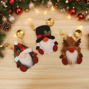 Three Christmas gnome cutlery holders set with plaid and reindeer hats on wood background