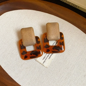 Detail of geometric vintage earrings with wood grain texture and amber resin pendant