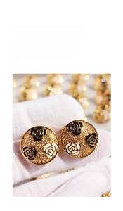 Detailed macro view of French vintage enamel camellia earrings with cubic zirconia inlay