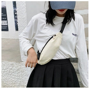 Street style view of cream canvas crossbody bag with black strap on a model
