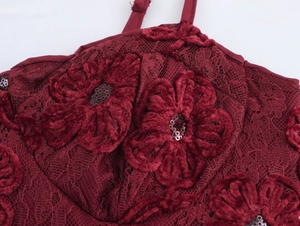 Close-up of burgundy lace dress featuring 3D floral decoration with sparkling sequins