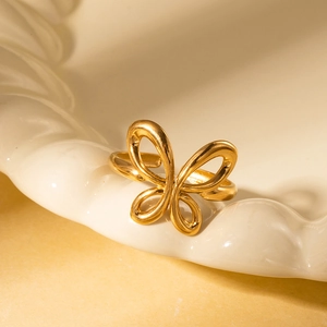 Detailed close-up of a gold hollow butterfly titanium ring on a white ceramic dish
