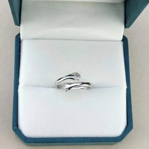 Close-up of silver hugging hands ring presented in a luxury blue velvet jewelry box