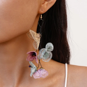 Close-up of handmade fabric flower tassel earrings showing texture and draping on model